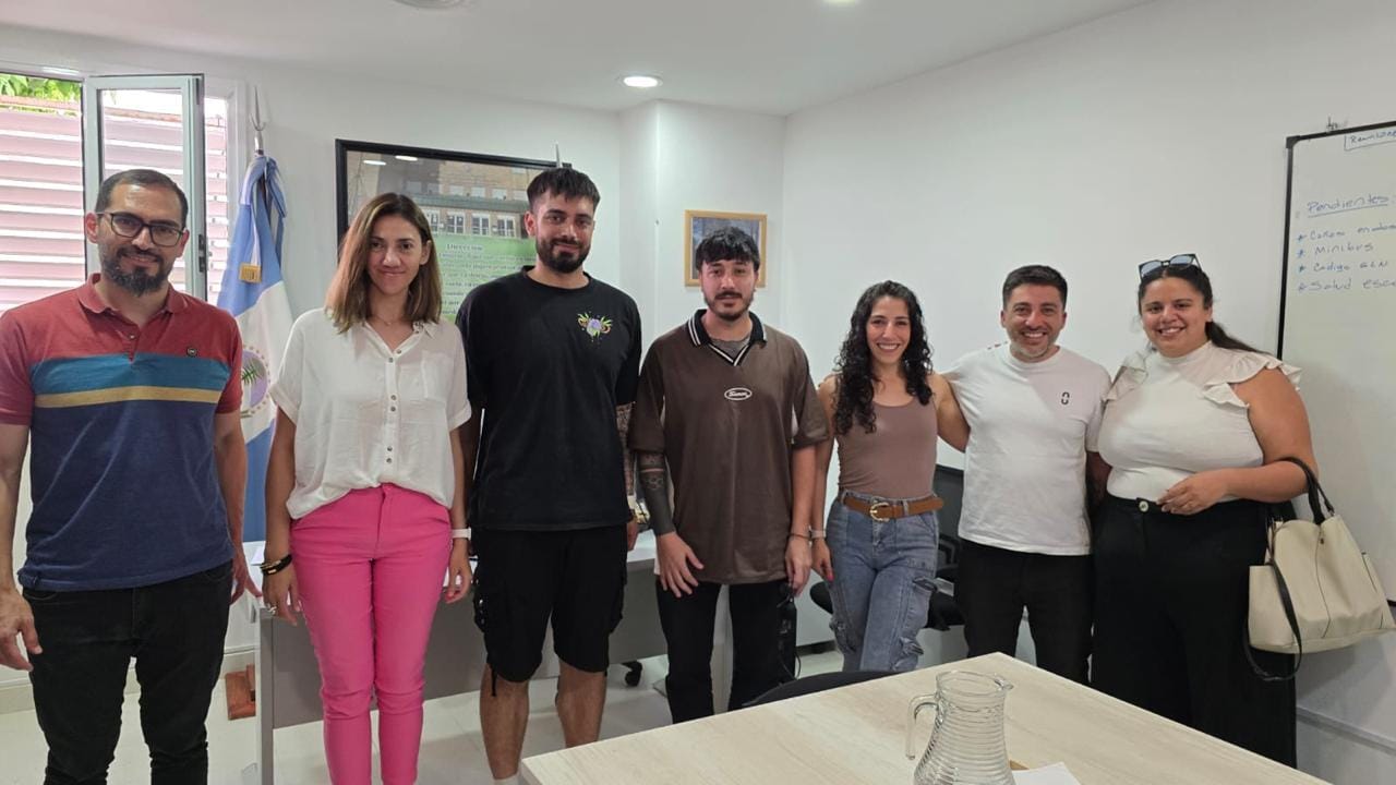 Equipo de pie en una oficina, junto a una bandera argentina